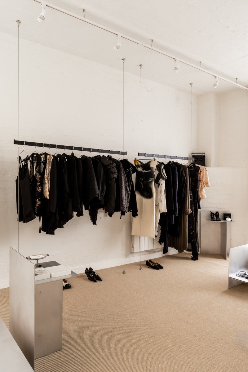 Dark archive garments arranged beside a daylight window in the Mondō studio.
